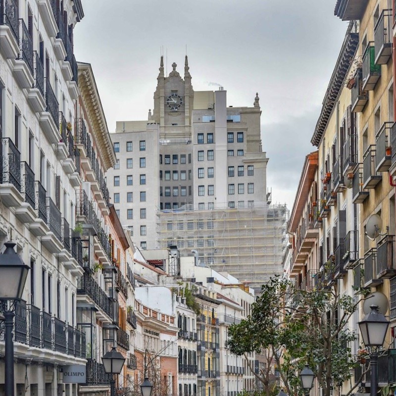 Vista de una calle con edificios residenciales típicos del barrio Universidad (Malasaña) en Madrid, mostrando el tipo de viviendas disponibles para inversión en alquiler.