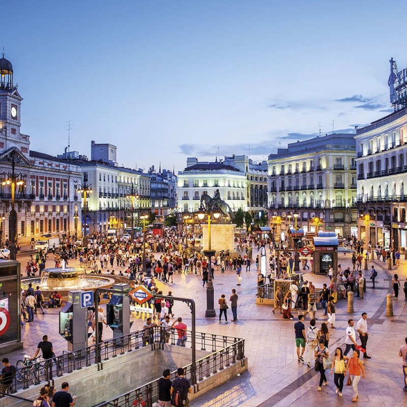 Vista aérea de la Puerta del Sol de Madrid al anochecer, mostrando el flujo de gente y elementos icónicos del barrio, ideal para quienes buscan invertir en el barrio Sol de Madrid.